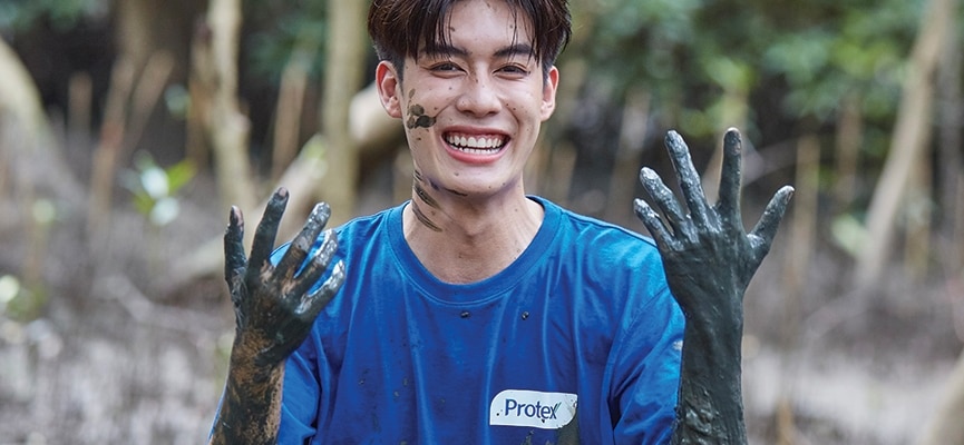 ชายในเสื้อเชิ้ตสีน้ำเงิน มือมีโคลนติดอยู่ สื่อถึงการทำงานในสวนหรือกิจกรรมที่เกี่ยวข้องกับดิน