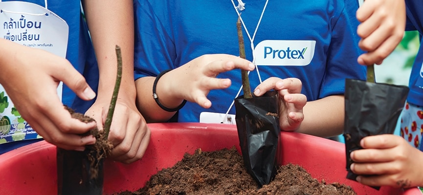 เด็ก ๆ กำลังปลูกเมล็ดในกระถางสีแดง สื่อถึงการเรียนรู้และการเติบโตในธรรมชาติ