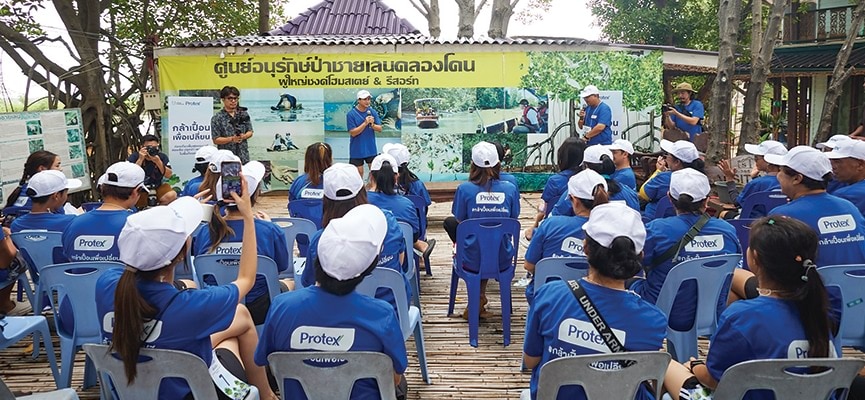 ผู้คนในเสื้อสีน้ำเงินนั่งเรียงกันบนเก้าอี้ สื่อถึงความร่วมมือและการทำงานเป็นทีม