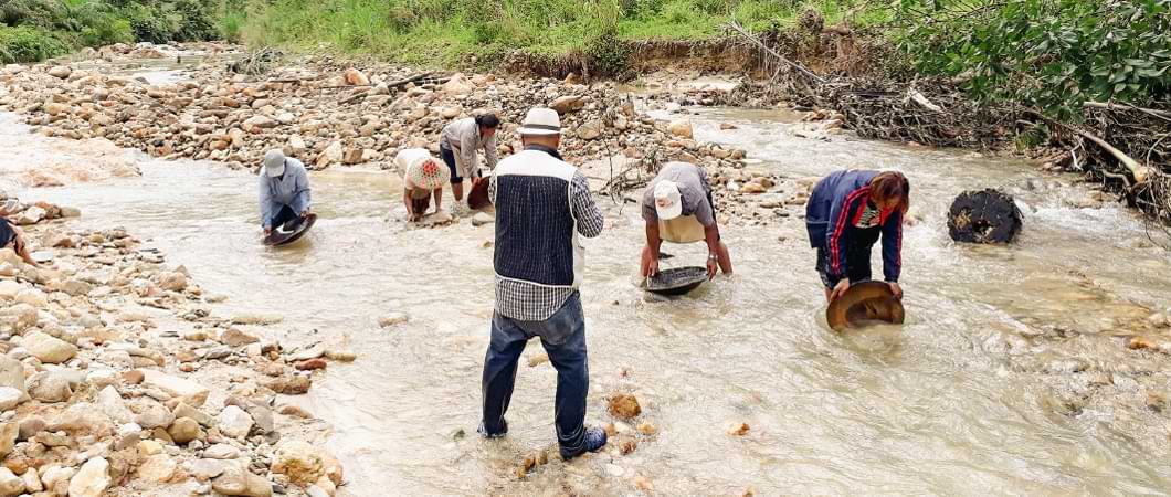 กลุ่มคนทำงานในลำธารที่มีหินกระจายอยู่ สื่อถึงการทำงานร่วมกันในธรรมชาติ 