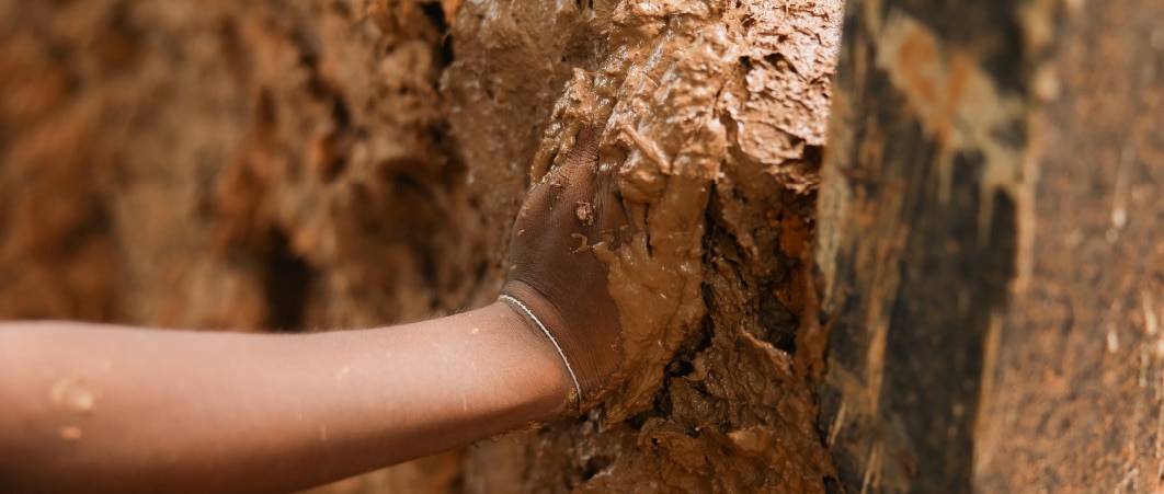 มือของคนหนึ่งแตะผนังที่มีโคลนปกคลุม สื่อถึงการสำรวจและการมีปฏิสัมพันธ์กับพื้นผิวธรรมชาติ