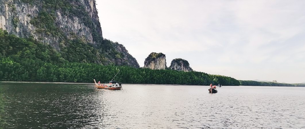 เรือสองลำลอยอยู่บนผิวน้ำใกล้ภูเขา สภาพแวดล้อมสงบและสวยงาม
