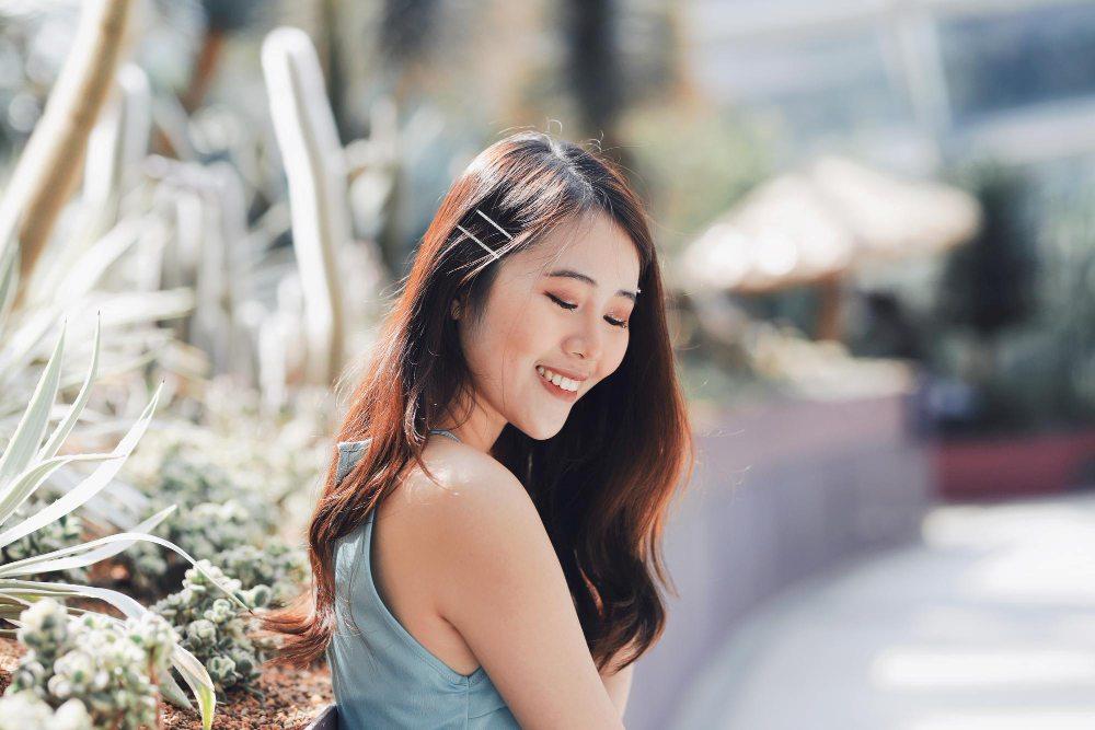 ผู้หญิงยิ้มอย่างมีความสุขกลางแจ้ง สื่อถึงความมั่นใจและความงามตามธรรมชาติ