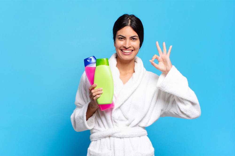 สาวในผ้าคลุมอาบน้ำที่กำลังเลือกผลิตภัณฑ์ดูแลผิว