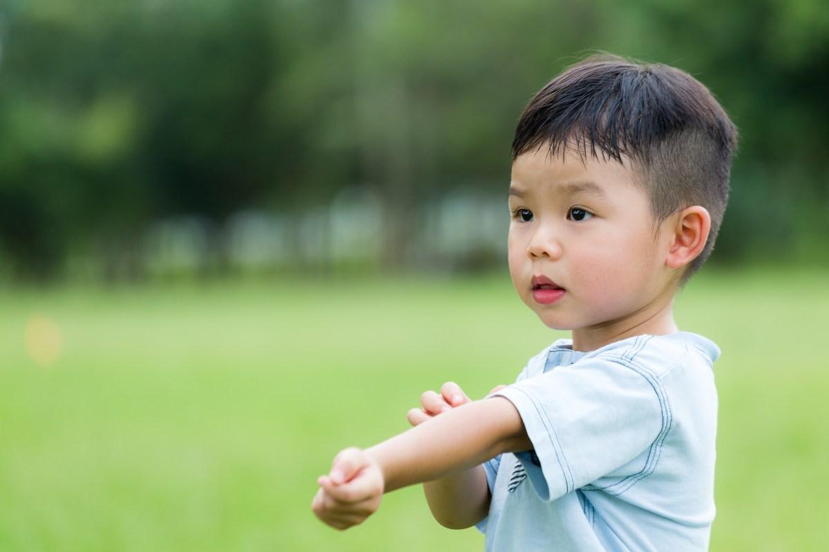 เด็กชายกำลังยืดแขนออกกำลังกายกลางแจ้งบนสนามหญ้า