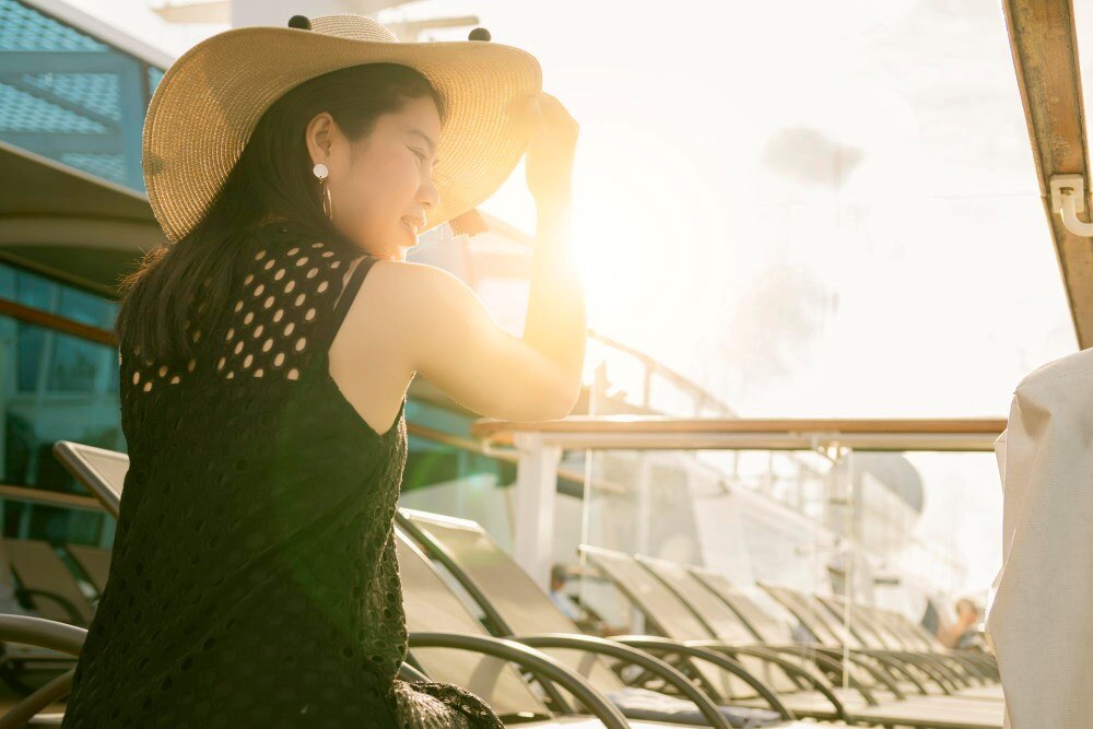 หญิงที่อยู่ในสถานที่กลางแจ้งที่สวมหมวกปีกกว้างขนาดใหญ่กำลังกันแดดที่ร้อนระอุ หญิงที่อยู่ในสถานที่กลางแจ้งที่สวมหมวกปีกกว้างขนาดใหญ่กำลังกันแดดที่ร้อนระอุ