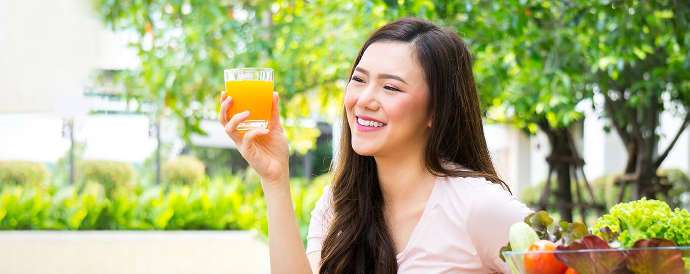 ผู้หญิงดื่มน้ำส้มที่ให้วิตามินซี